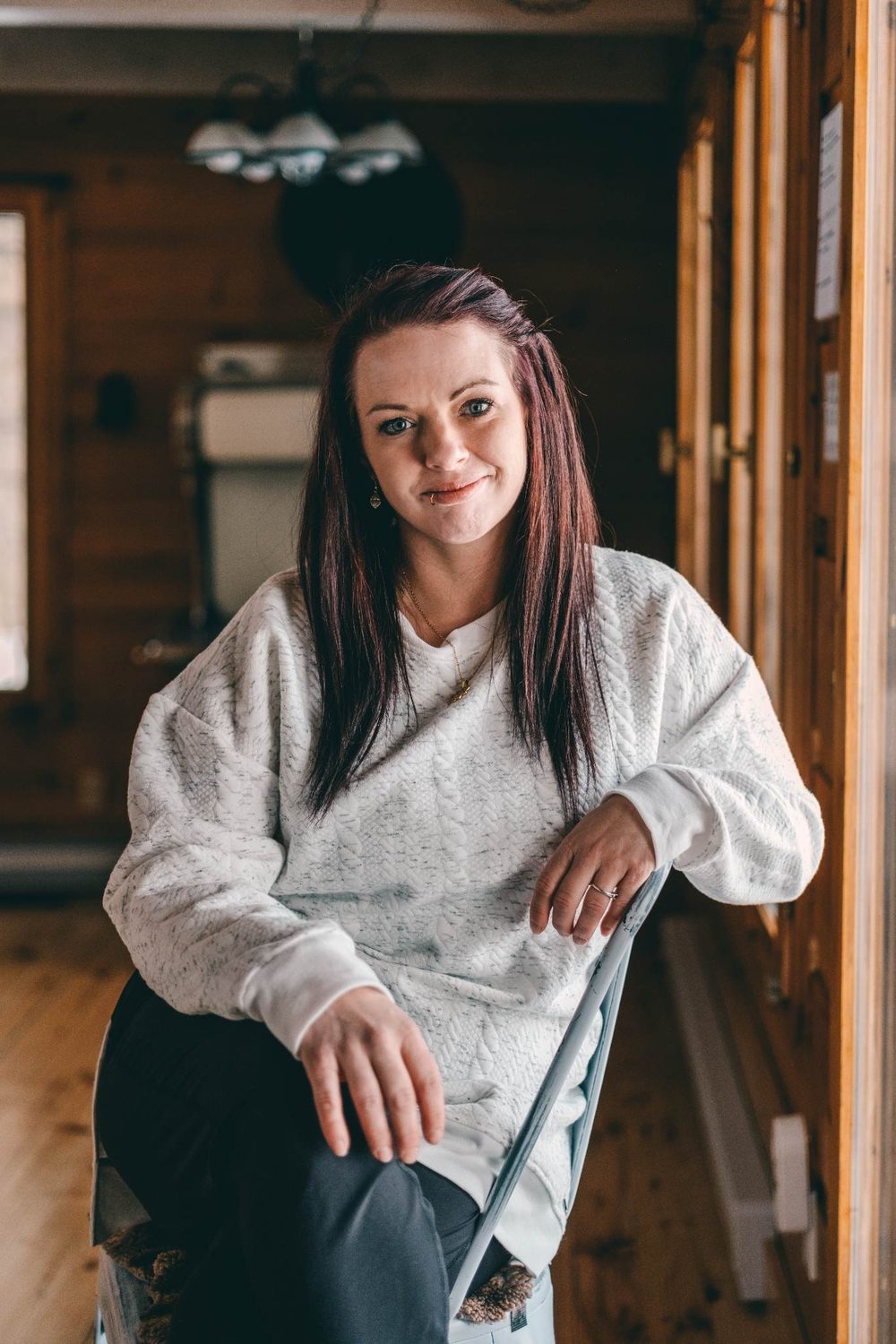 Carolane Landry, assise dans un chalet aux murs de bois.