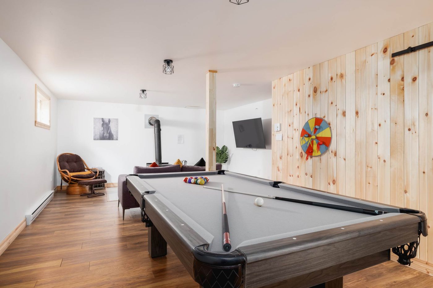 Salle de jeux avec table de billard et poêle à bois.